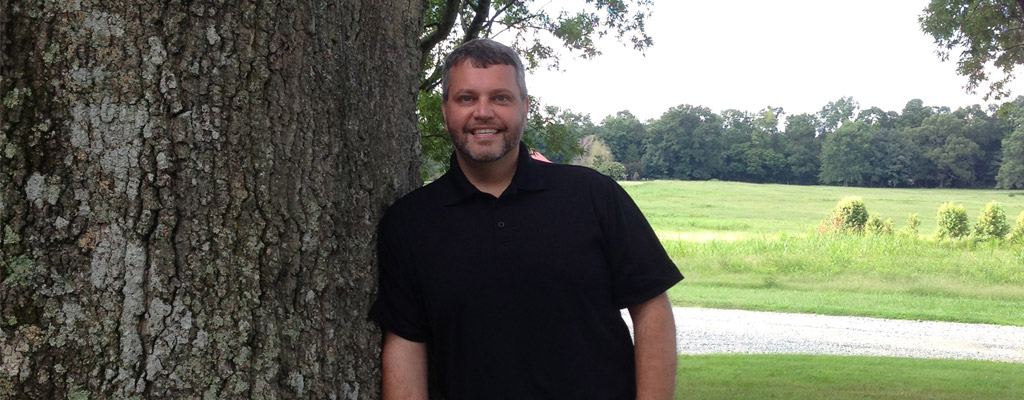 Massage Therapist John W Maynor poses by a beautiful oak tree at the entrance to BTI, the Body Therapy Institute in Siler City, NC.